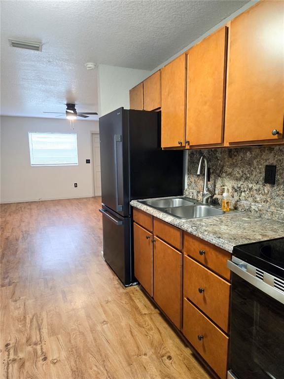 A kitchen features wood cabinets, a black refrigerator, and a stainless steel sink — 1517 S TAYLOR ROAD, SEFFNER, FL