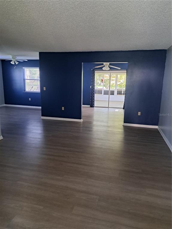 A living room with dark blue walls, light wood-look flooring, and a sliding glass door — 5618 ROSEWALL CIRCLE, LEESBURG, FL