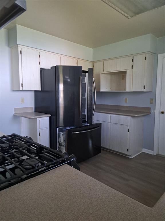A kitchen features light-colored cabinets, tan countertops, and a black refrigerator — 5618 ROSEWALL CIRCLE, LEESBURG, FL