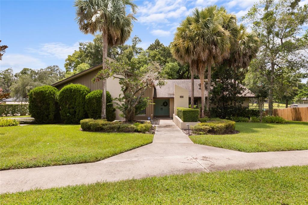 A single-story house with a concrete walkway, palm trees, and manicured landscaping in the front yard — 956 STONEWOOD LANE, MAITLAND, FL