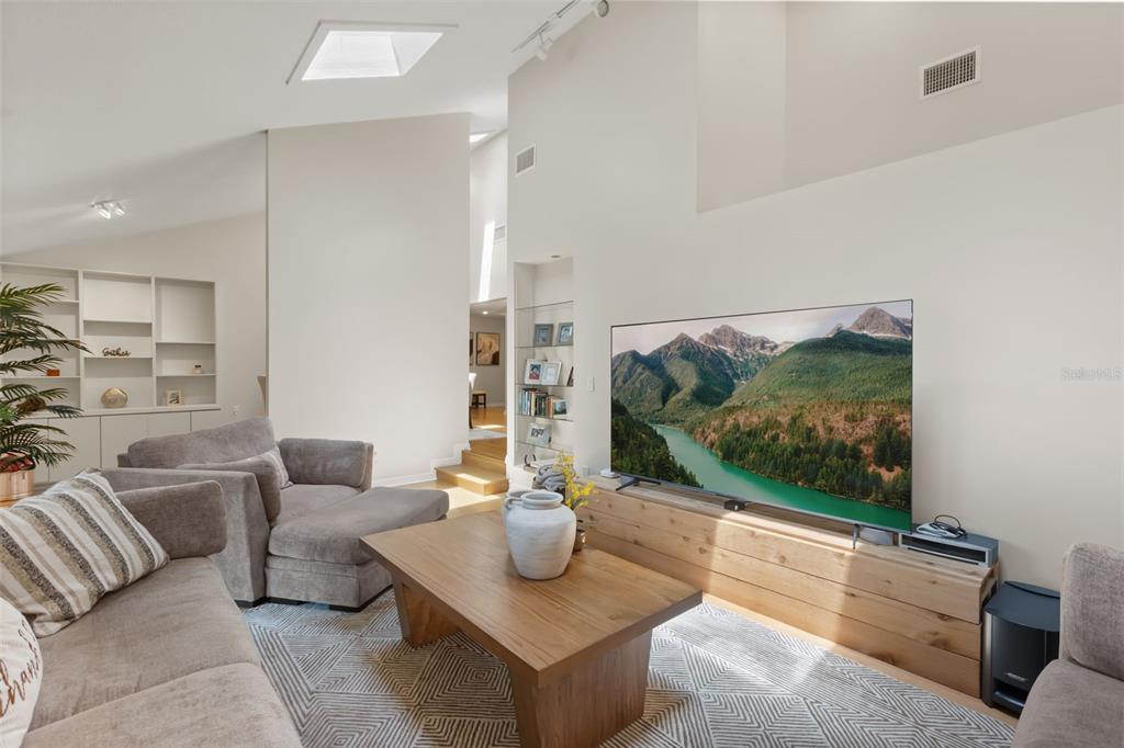 A living room features a large television on a wood console, gray sofas, and shelving — 956 STONEWOOD LANE, MAITLAND, FL