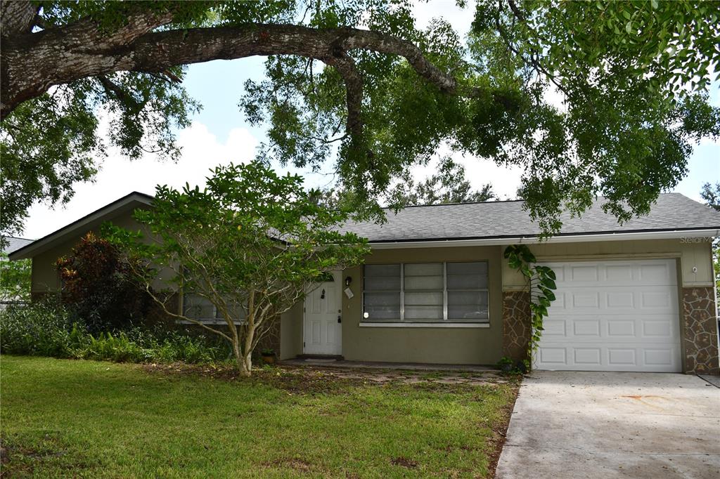 A single-story house with a white garage door, stone accents, and a large shade tree — 1591 SUNKIST WAY, FORT MYERS, FL