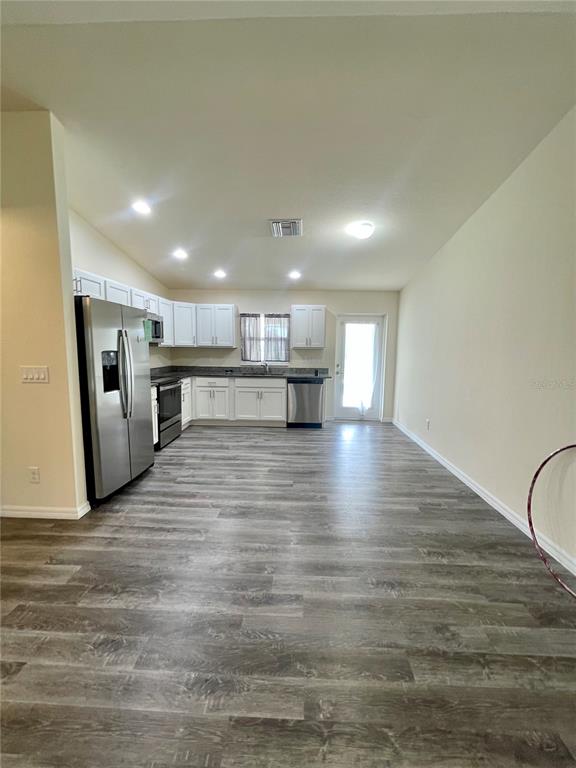 A kitchen with white cabinets, stainless steel appliances, and wood-look flooring in an open space — 5029 W HUMMINGBIRD DRIVE, LABELLE, FL