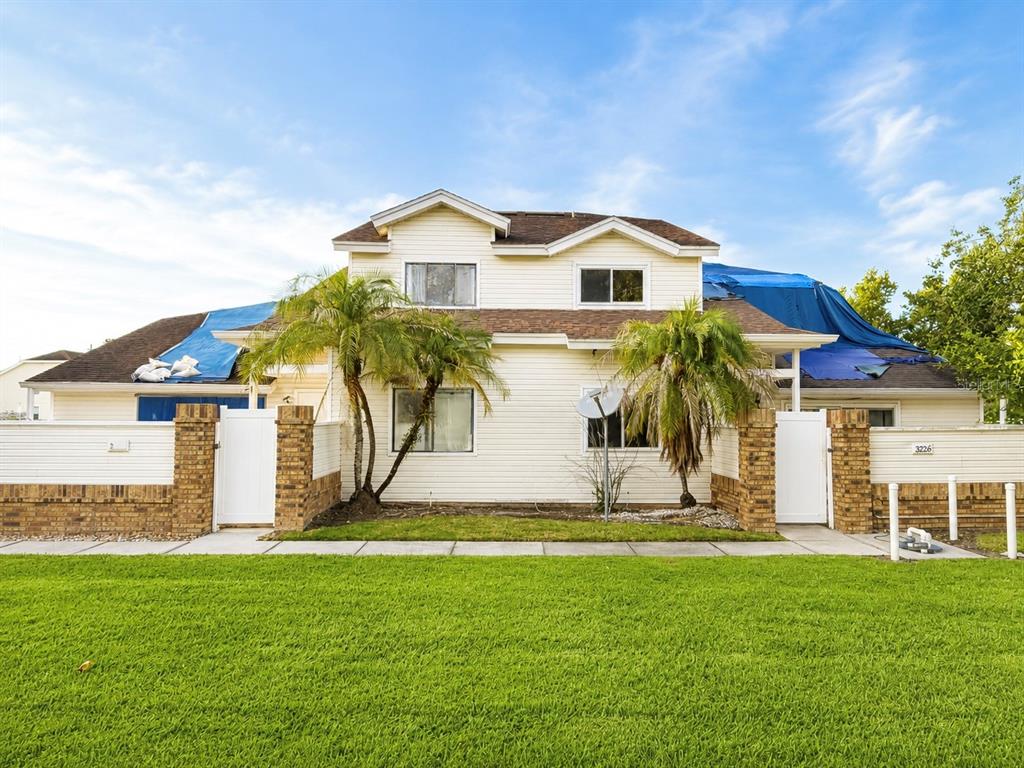 A two-story house with light siding and blue tarps covering parts of the roof — 3226 RIO GRANDE TRL UNIT 3226, KISSIMMEE, FL