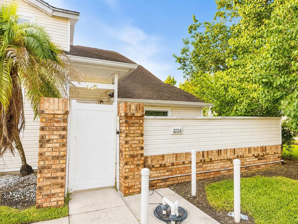 A white gate with brick pillars stands in front of a house with siding — 3226 RIO GRANDE TRL UNIT 3226, KISSIMMEE, FL