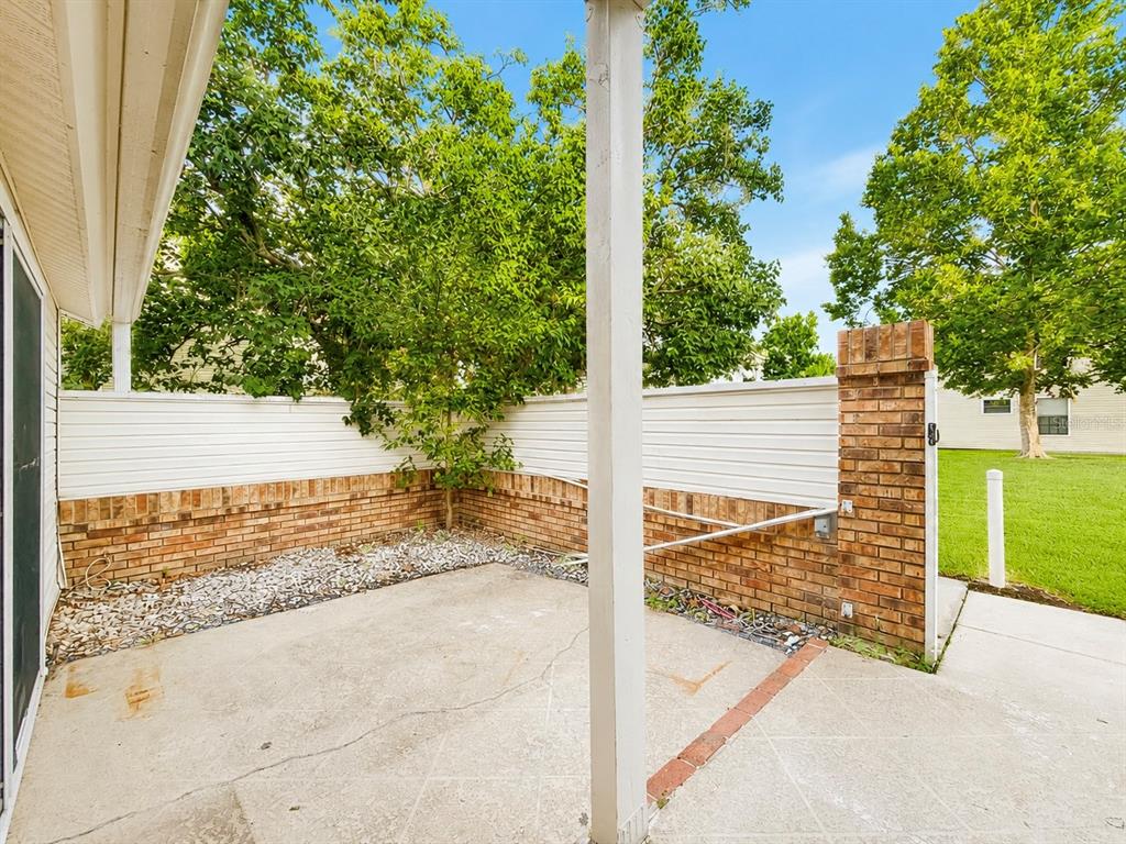 A concrete patio features a brick and white vinyl privacy fence with a support post — 3226 RIO GRANDE TRL UNIT 3226, KISSIMMEE, FL