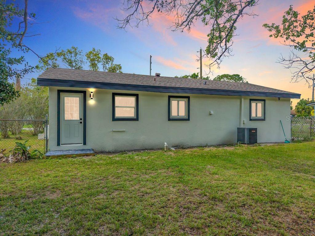 The exterior of a single-story house with light green stucco walls and a dark roof — 825 E CHURCH AVE, LONGWOOD, FL