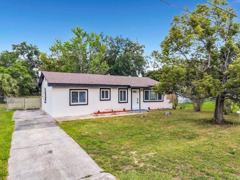 A single-story house with a white exterior, dark trim, and a concrete driveway — 825 E CHURCH AVE, LONGWOOD, FL