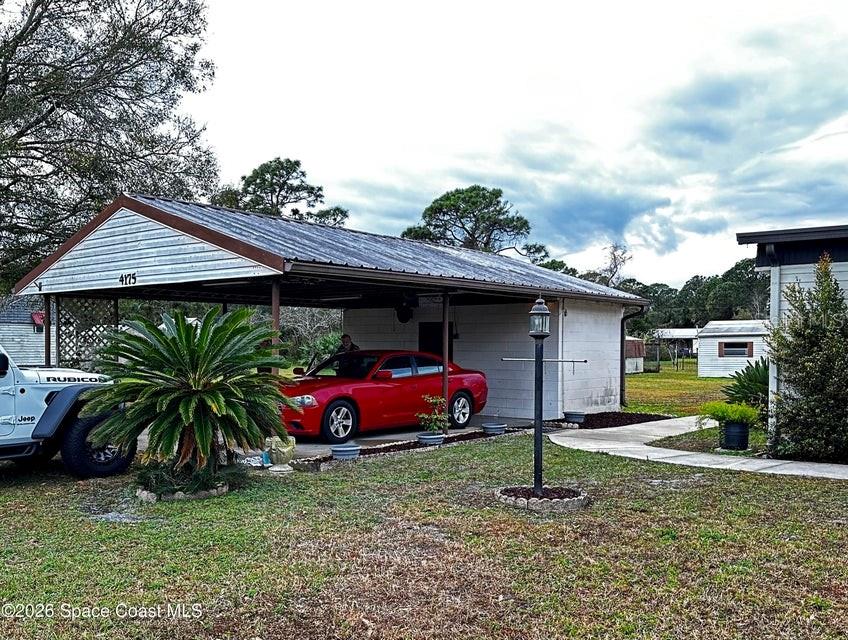A red sedan is parked under a metal carport next to a white Jeep — 4175 HESS AVENUE, COCOA, FL
