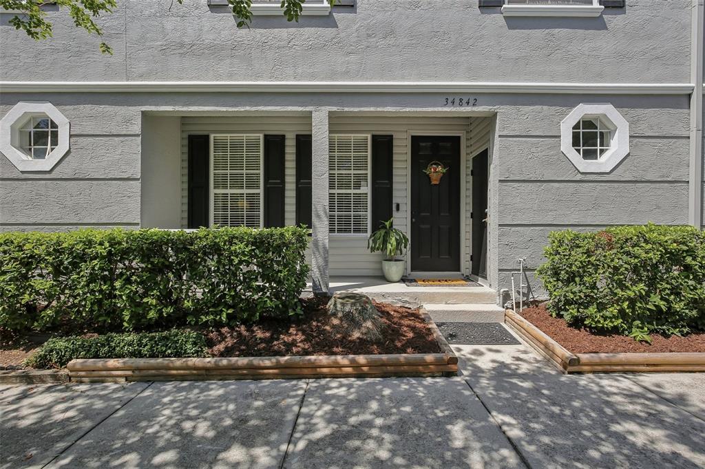 A living room features wood flooring, a television console, brown furniture, and a staircase — 34842 TEEVIEW LANE, ZEPHYRHILLS, FL