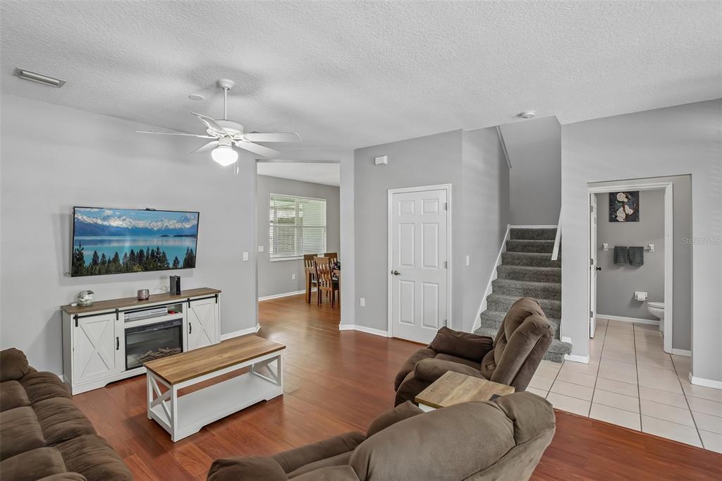 A living room features brown recliners, wood-look flooring, a ceiling fan, and a staircase — 34842 TEEVIEW LANE, ZEPHYRHILLS, FL