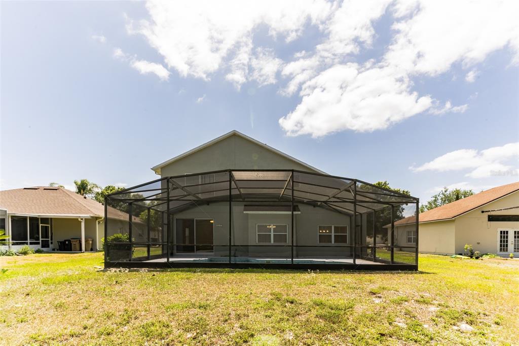 The exterior rear view of a two-story house features a screened-in pool enclosure — 2433 HURON CIRCLE, KISSIMMEE, FL