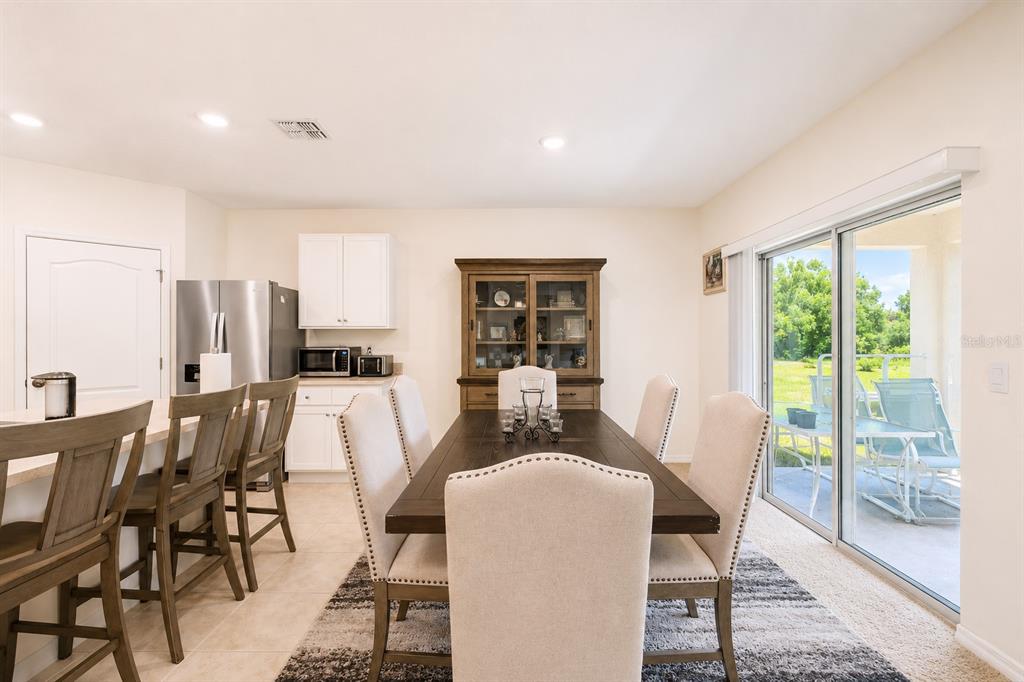 A dining area with a wooden table, upholstered chairs, and a sliding glass door — 3221 CARPENTARIA DRIVE, NEW SMYRNA BEACH, FL
