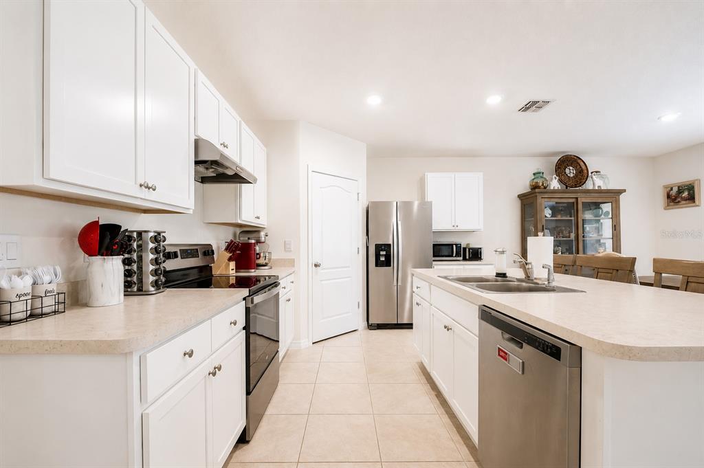 A kitchen with white cabinets, stainless steel appliances, and a central island with a sink — 3221 CARPENTARIA DRIVE, NEW SMYRNA BEACH, FL