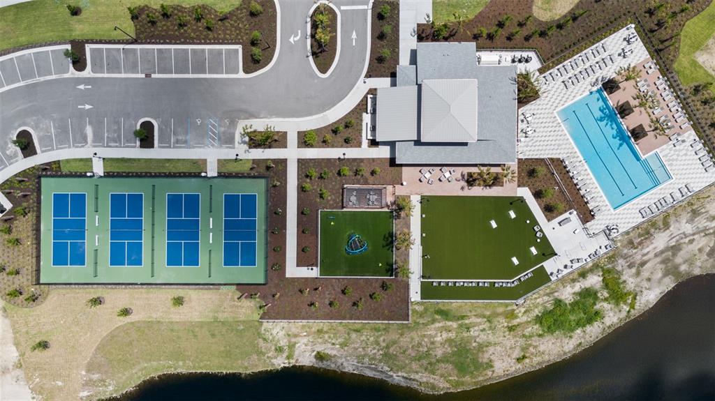 Aerial view of a community amenity center featuring a swimming pool, pickleball courts, and landscaping — 282 HOLLY BANK AVENUE, NOKOMIS, FL