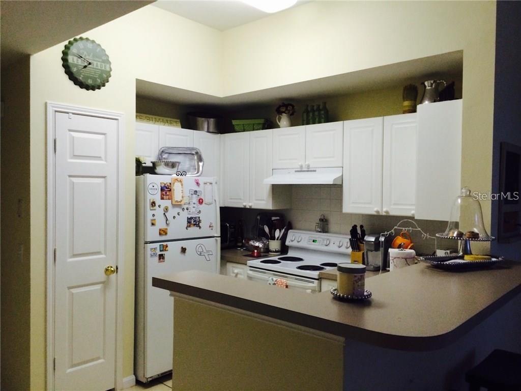 A kitchen features white cabinets, a white refrigerator, and a breakfast bar with countertops — 229 LONGVIEW AVENUE UNIT 5303, CELEBRATION, FL