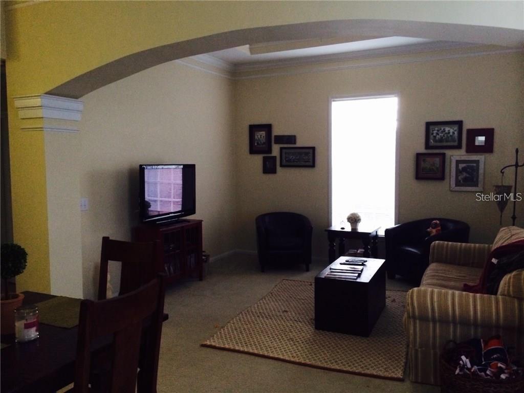 A living room features a television, two armchairs, a striped sofa, and a coffee table — 229 LONGVIEW AVENUE UNIT 5303, CELEBRATION, FL