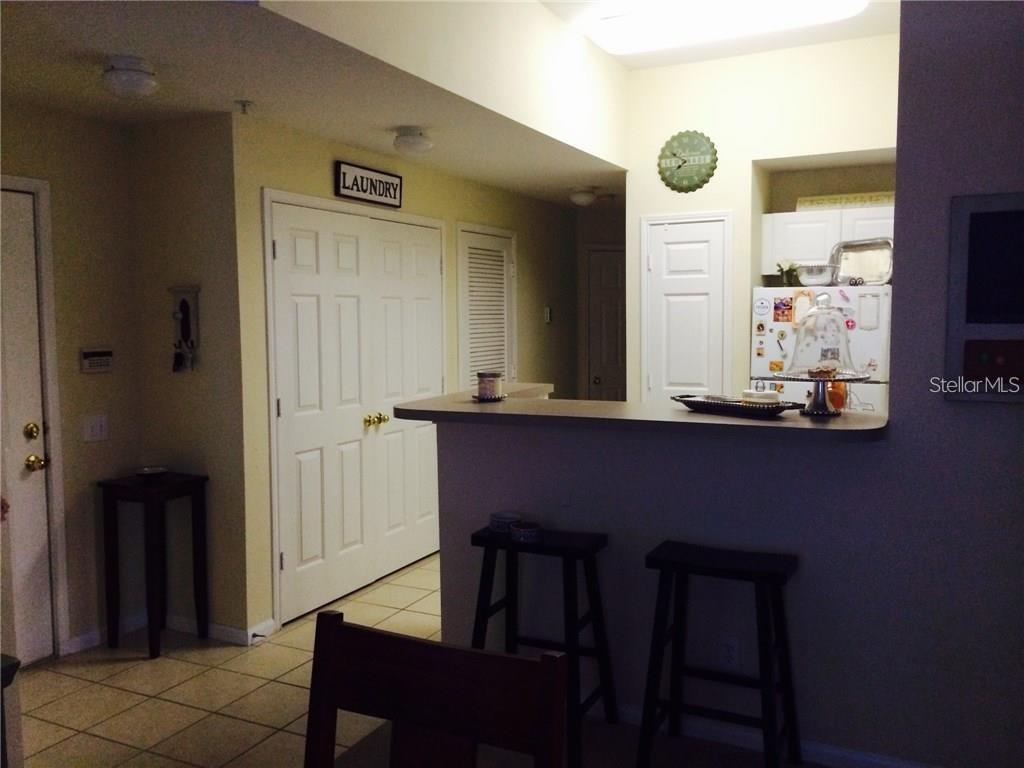 A kitchen with a breakfast bar, two stools, and a laundry closet door — 229 LONGVIEW AVENUE UNIT 5303, CELEBRATION, FL