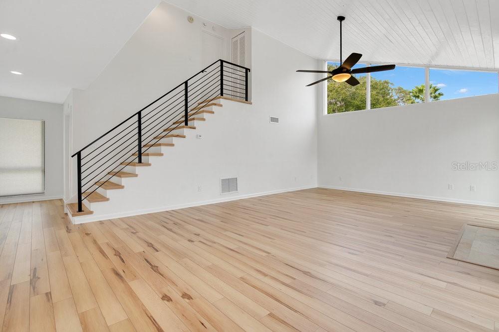 A bright living room features light wood floors, a vaulted ceiling, and a modern staircase — 905 MAIN STREET, WINDERMERE, FL