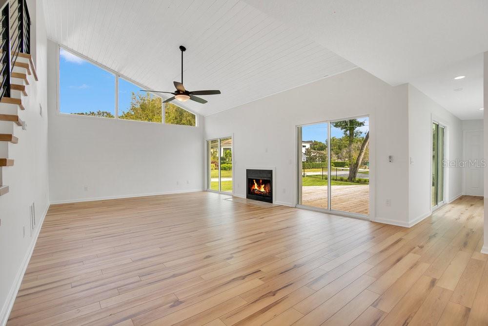 A bright living room features light wood floors, a vaulted ceiling, and a fireplace — 905 MAIN STREET, WINDERMERE, FL