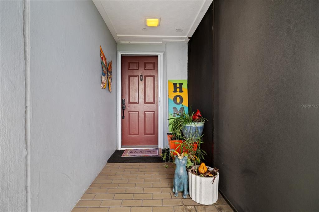 A covered entryway features a red front door, tiled flooring, and decorative potted plants — 2780 N RIVERSIDE DRIVE UNIT 805, TAMPA, FL