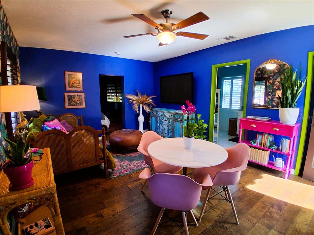 A vibrant living and dining room features blue walls, pink chairs, and a round table — 451 WOODLAND DRIVE, SARASOTA, FL