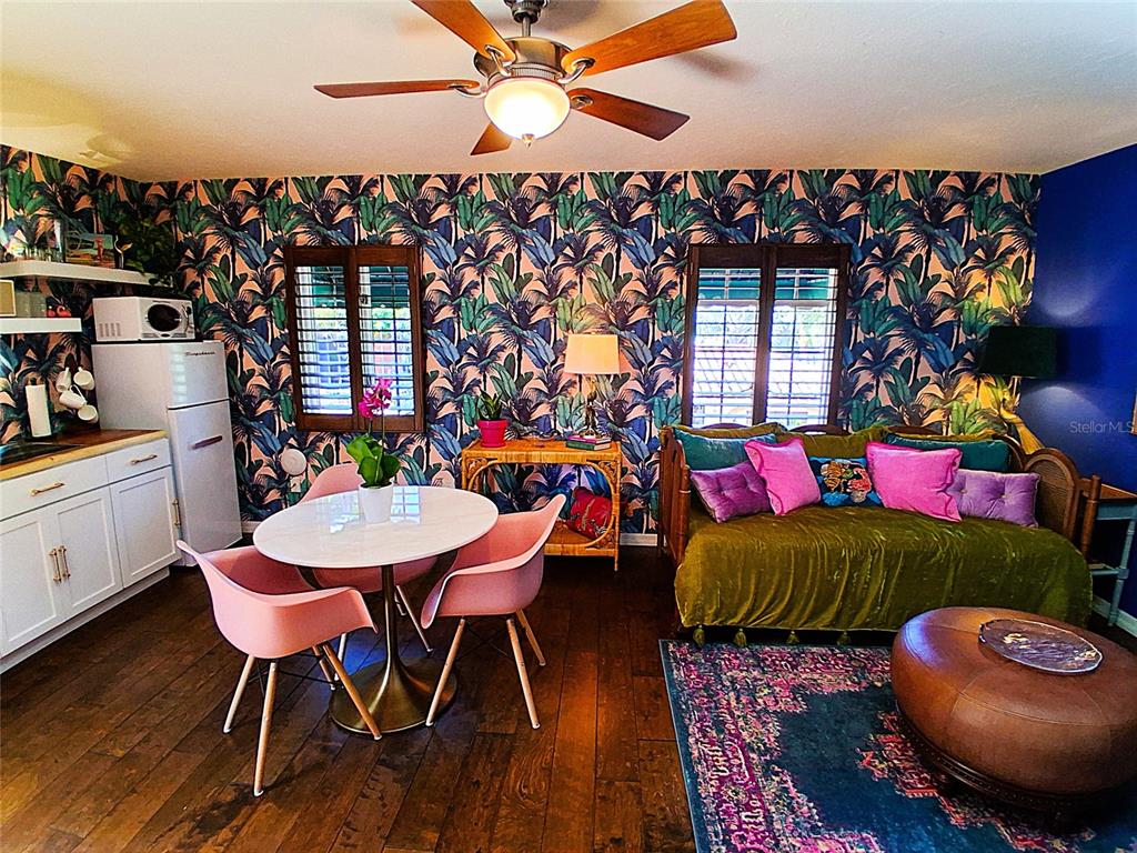 A living and dining area features tropical wallpaper, a velvet daybed, and pink dining chairs — 451 WOODLAND DRIVE, SARASOTA, FL
