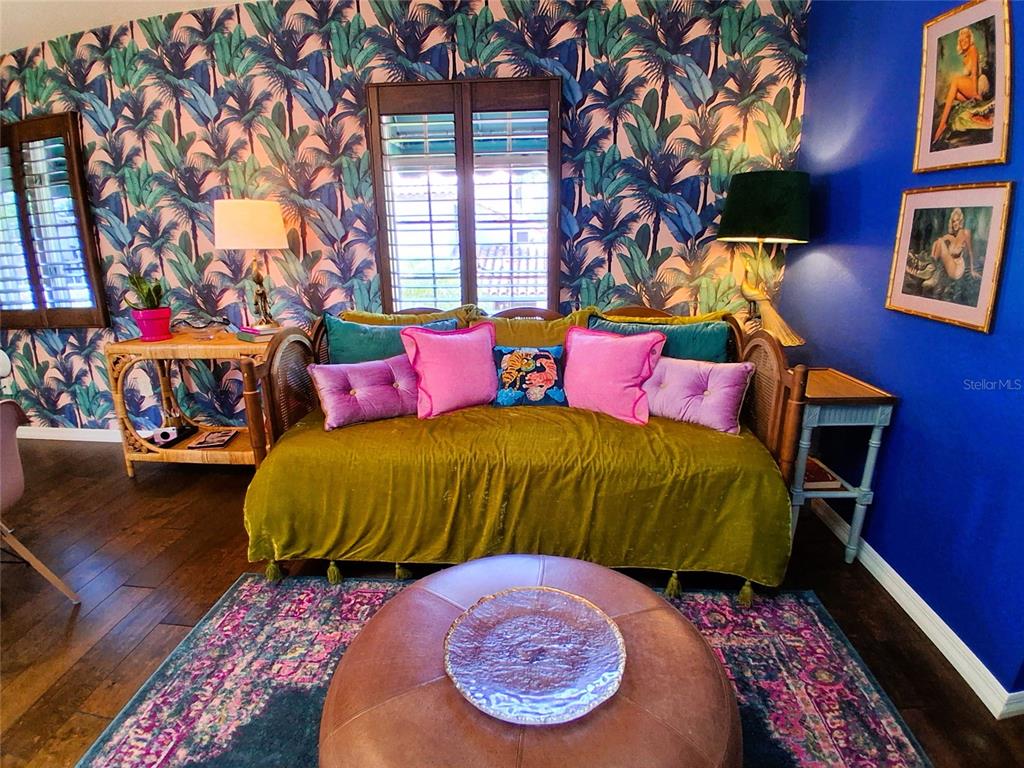A living room features a daybed, palm-patterned wallpaper, a blue accent wall, and an ottoman — 451 WOODLAND DRIVE, SARASOTA, FL