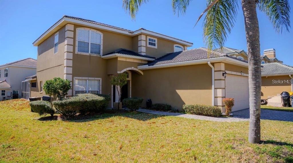 A two-story tan stucco house with a tiled roof and a two-car garage — 416 VISTA LOOP, DAVENPORT, FL