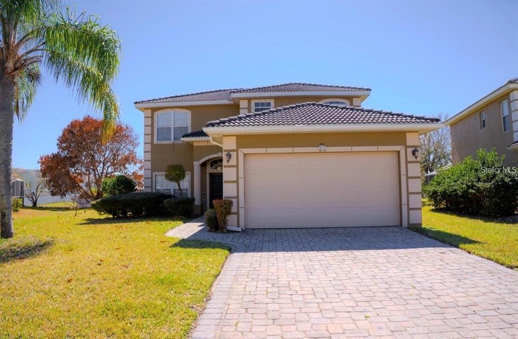 A two-story suburban house with a tan stucco exterior and a paved driveway — 416 VISTA LOOP, DAVENPORT, FL