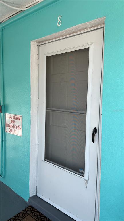 A white screen door with the number eight above it on a bright teal wall — 680 71ST AVENUE UNIT 8, ST PETE BEACH, FL