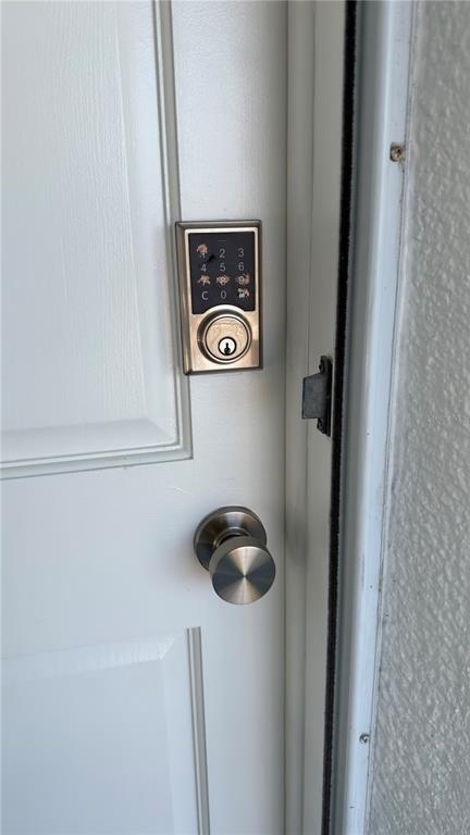 A white door features a brushed nickel doorknob and a digital keypad deadbolt lock — 680 71ST AVENUE UNIT 8, ST PETE BEACH, FL