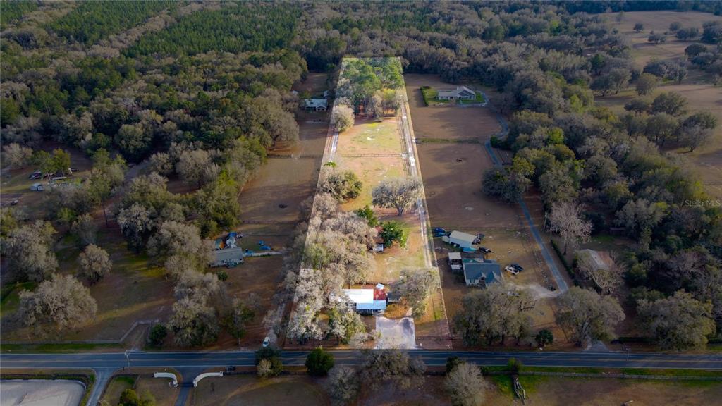 An aerial view shows a long, narrow residential property with a house and fenced pastures — 1154 SE 95TH STREET, OCALA, FL