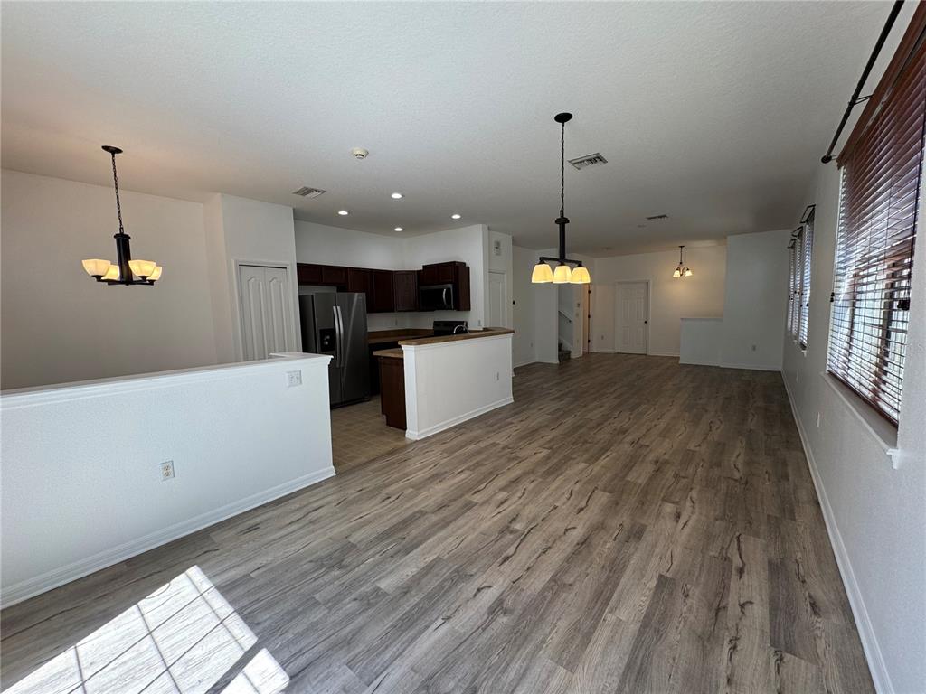 An open-concept living and dining area features wood-look flooring and a kitchen with dark cabinetry — 9124 MOONLIT MEADOWS LOOP, RIVERVIEW, FL