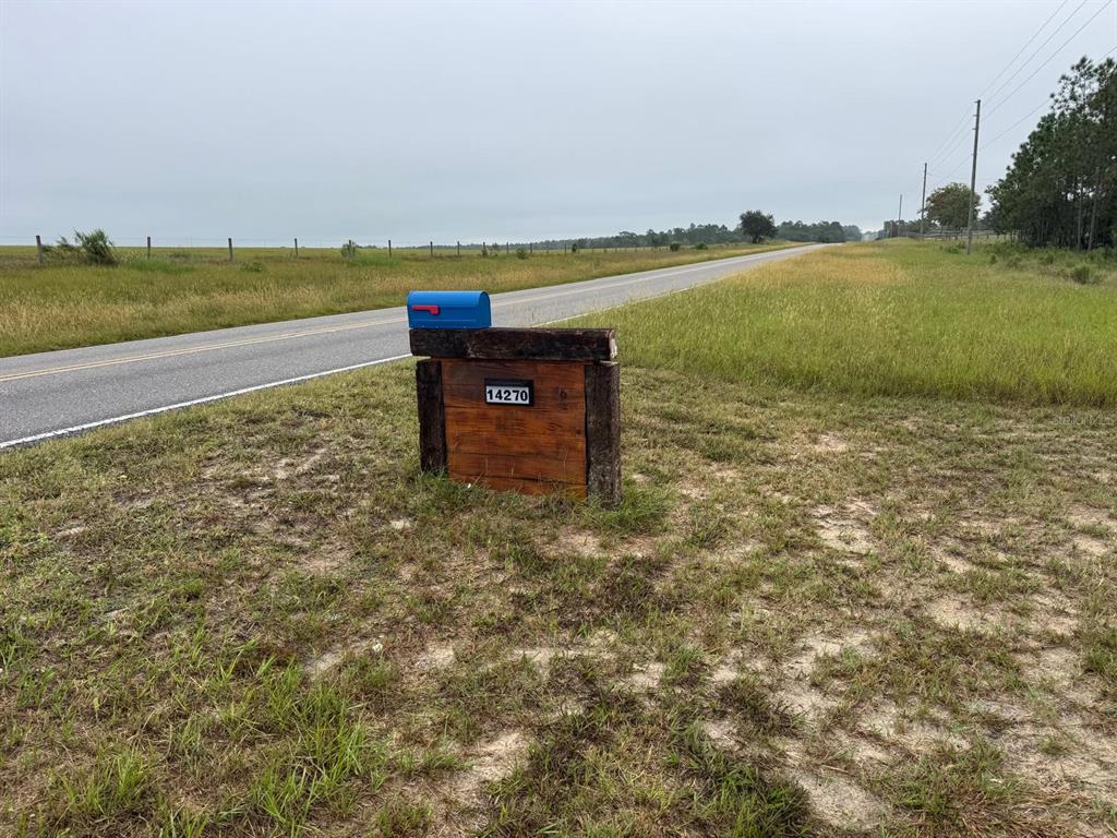 An aerial view shows a large, fenced grassy pasture with a building in the background — 14270 SE 60 STREET, MORRISTON, FL