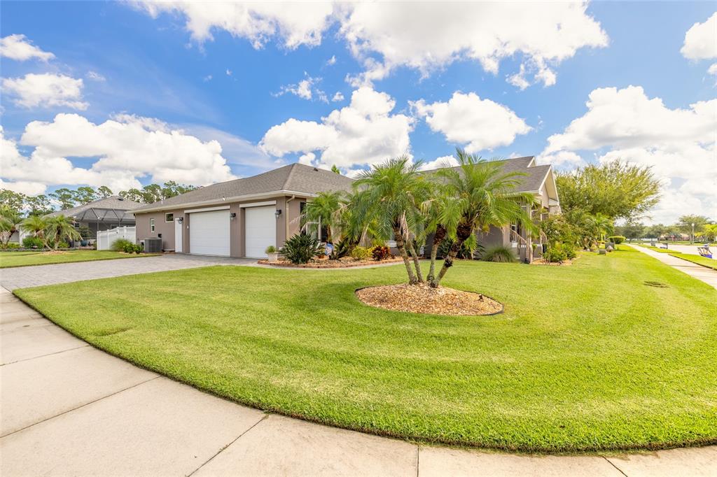 A single-story house with a two-car garage and a landscaped front yard under a blue sky — 3659 CESI AVENUE, NEW SMYRNA BEACH, FL