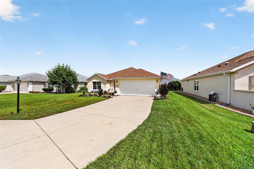 A single-story house with a white garage door, beige siding, and a concrete driveway — 11985 SE 91ST CIRCLE, SUMMERFIELD, FL