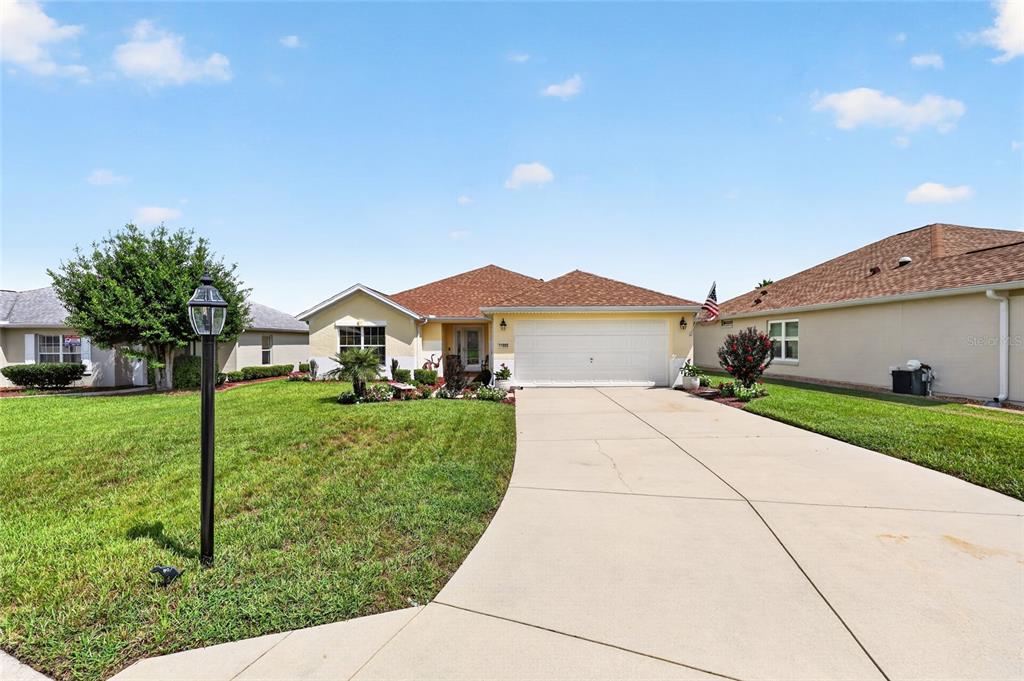 A single-story house with a yellow exterior, a two-car garage, and a concrete driveway — 11985 SE 91ST CIRCLE, SUMMERFIELD, FL