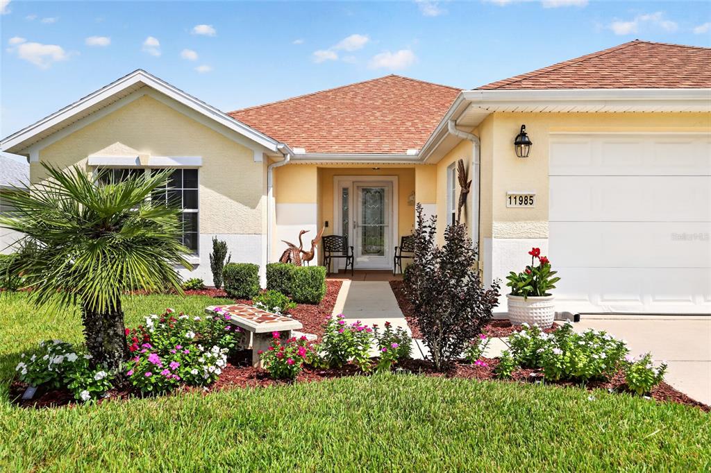 A single-story house with a yellow stucco exterior, a two-car garage, and a landscaped front yard — 11985 SE 91ST CIRCLE, SUMMERFIELD, FL