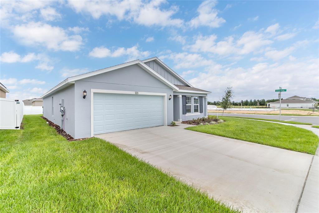 A blue single-story house with a two-car garage and a paved driveway — 123 BOTTLE BRUSH DRIVE, HAINES CITY, FL