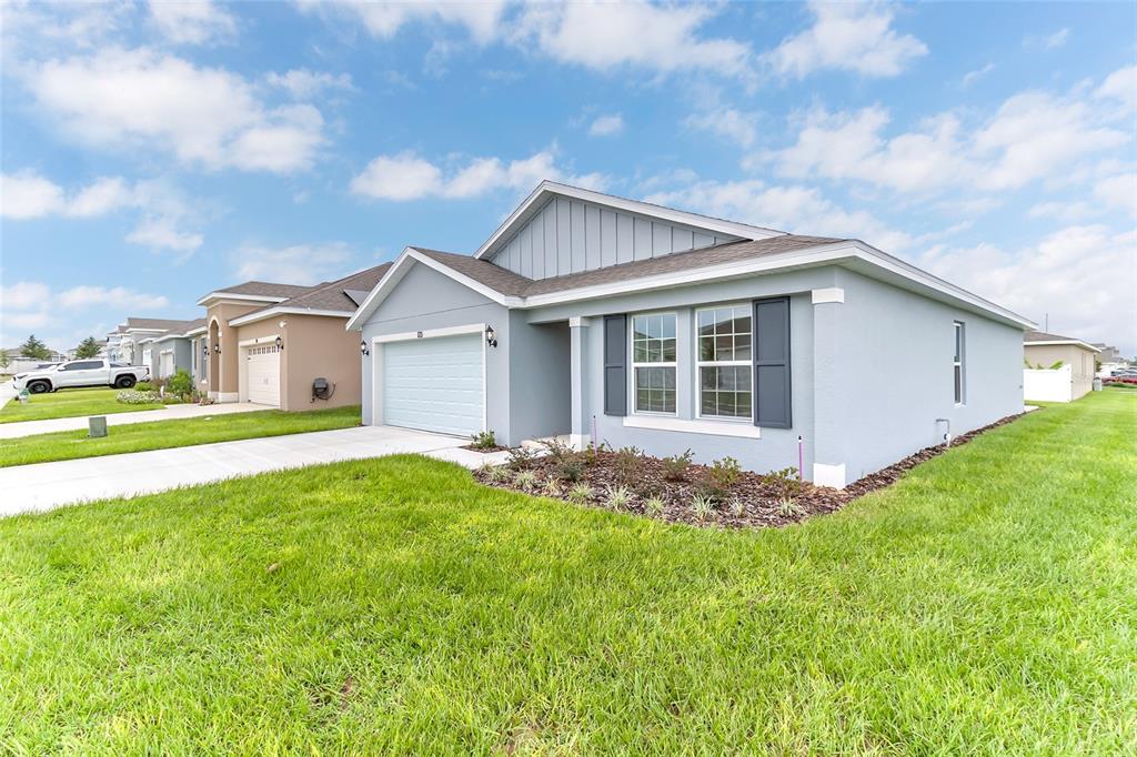 A modern kitchen features white cabinetry, a central island with bar seating, and stainless appliances — 123 BOTTLE BRUSH DRIVE, HAINES CITY, FL