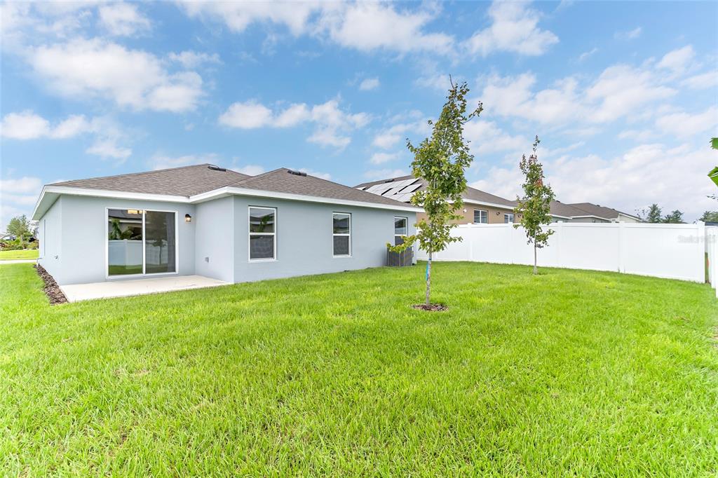 A living room features a white media console, a round wooden coffee table, and chairs — 123 BOTTLE BRUSH DRIVE, HAINES CITY, FL