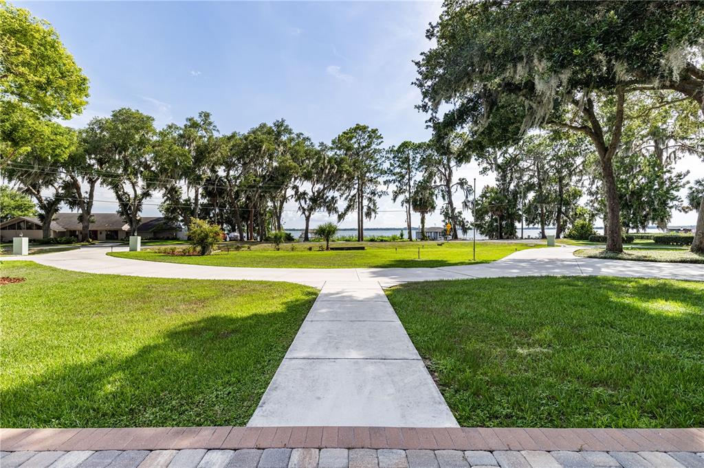 A glass-topped table and metal chairs sit on a wooden deck overlooking a lake — 32834 LAKESHORE DRIVE, TAVARES, FL