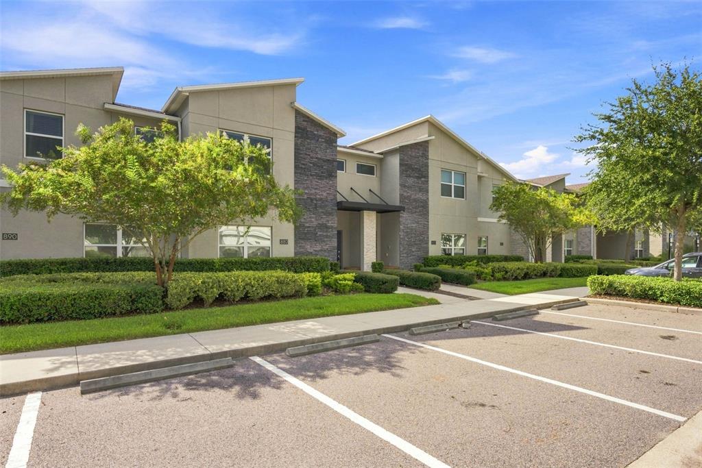 A multi-unit residential building with stone accents and a parking lot in the foreground — 880 PEBBLE BEACH DRIVE, DAVENPORT, FL