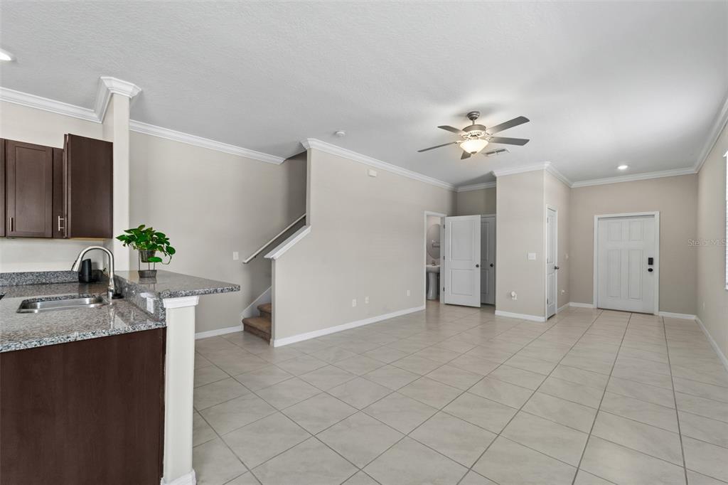 An open-concept living area features tile flooring, a kitchen island, and a staircase — 2188 CERULEAN SKY DRIVE, LUTZ, FL