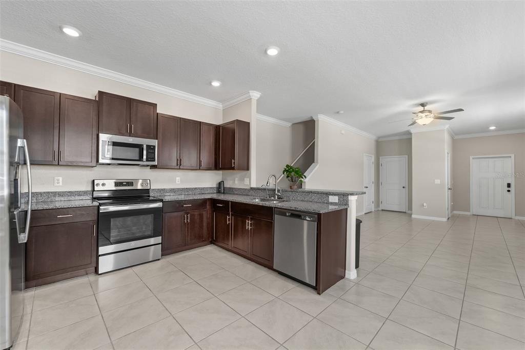 A kitchen with dark wood cabinets, granite countertops, and stainless steel appliances — 2188 CERULEAN SKY DRIVE, LUTZ, FL