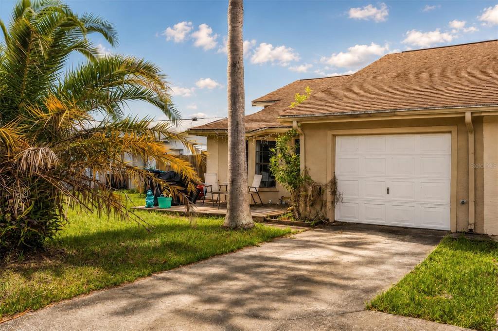 A single-story house with a white garage door, a concrete driveway, and a palm tree — 20644 MACON PARKWAY, ORLANDO, FL