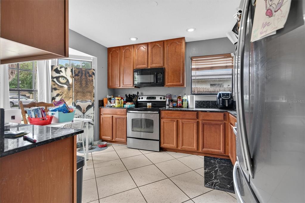 A kitchen features wood cabinets, stainless steel appliances, granite countertops, and a tiger-print window covering — 20644 MACON PARKWAY, ORLANDO, FL