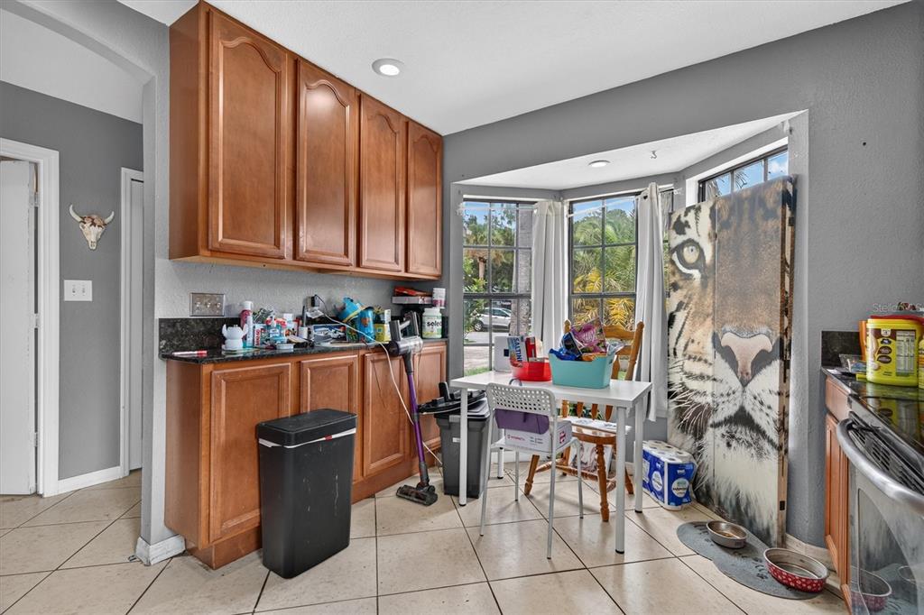 A kitchen dining area features wood cabinets, a bay window, and a large tiger-print screen — 20644 MACON PARKWAY, ORLANDO, FL