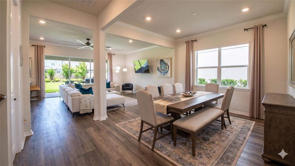 An open-concept living area features wood-look flooring, a sectional sofa, and a dining space — 13360 PANAMA BEACH COURT, ORLANDO, FL